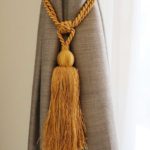 edle Quaste RHONE in Gold an Vorhang im Wohnzimmer • rideaux123.ch